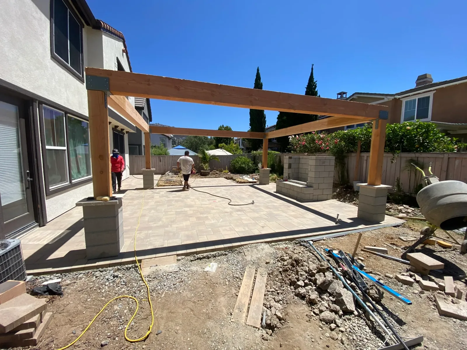 Outdoor kitchen with stainless cabinetry and fire feature under a patio cover in Encinitas